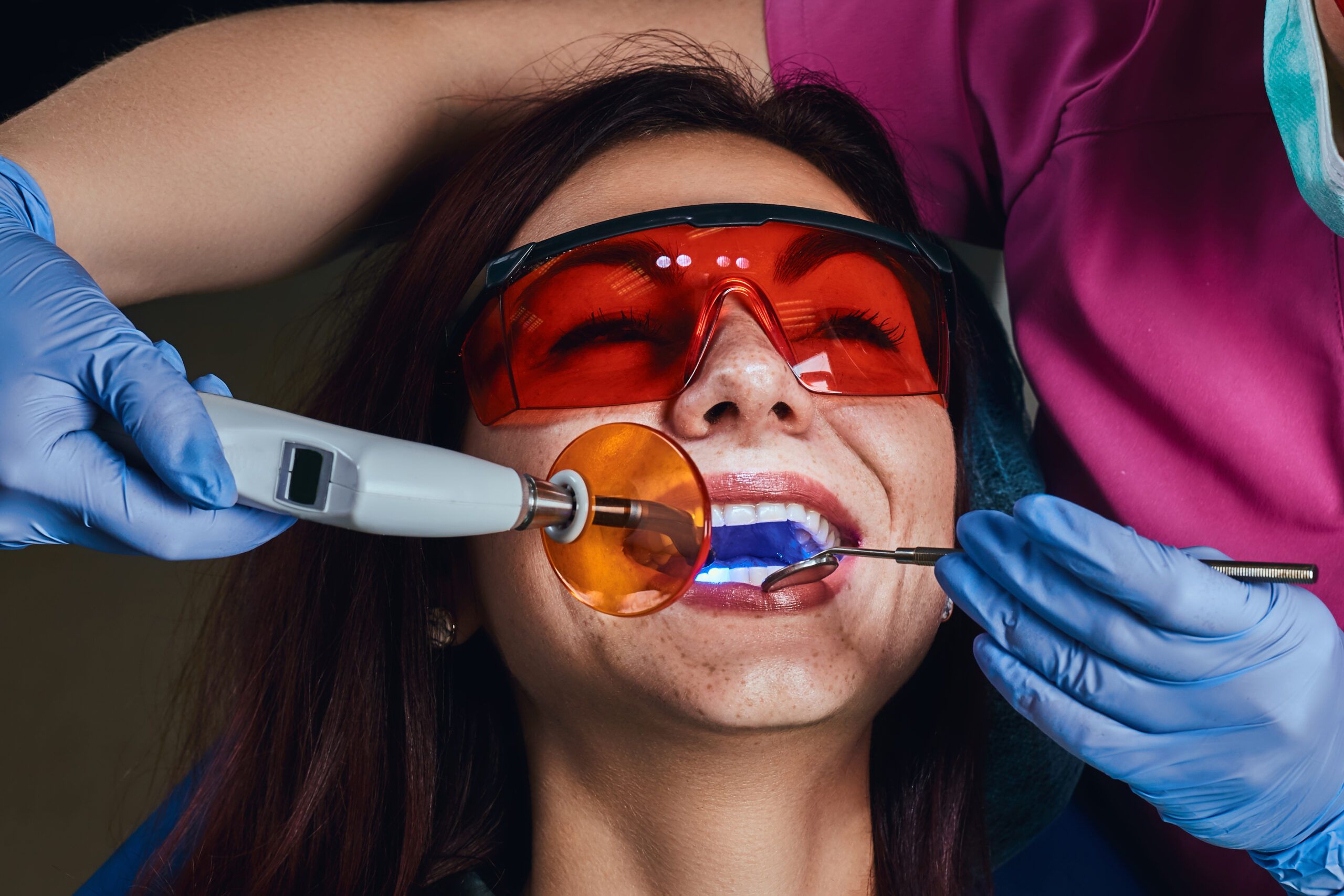 A dental professional applying a protective material to a patient’s teeth