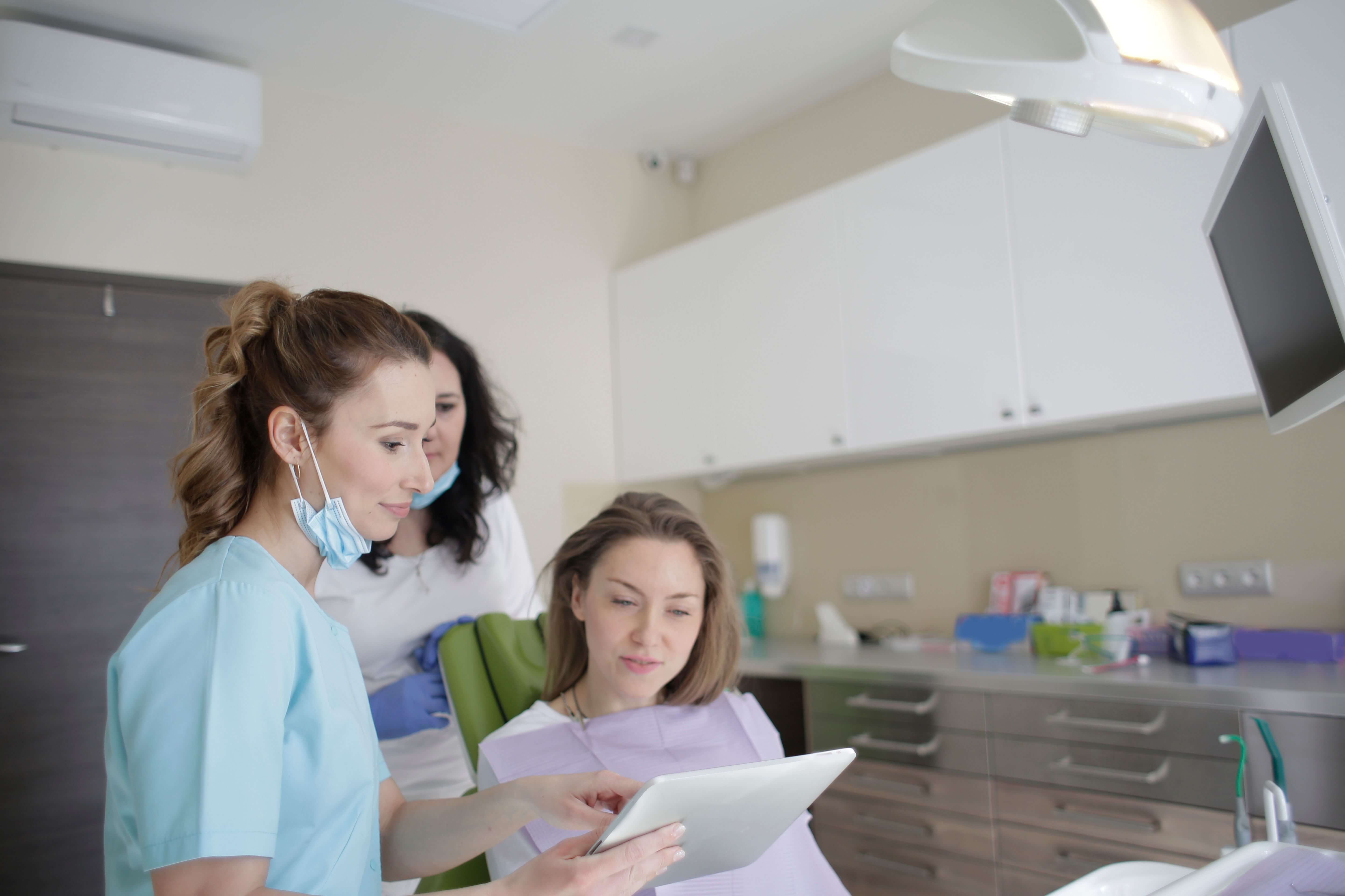 Dental professionals reviewing a tablet with a patient in a treatment room